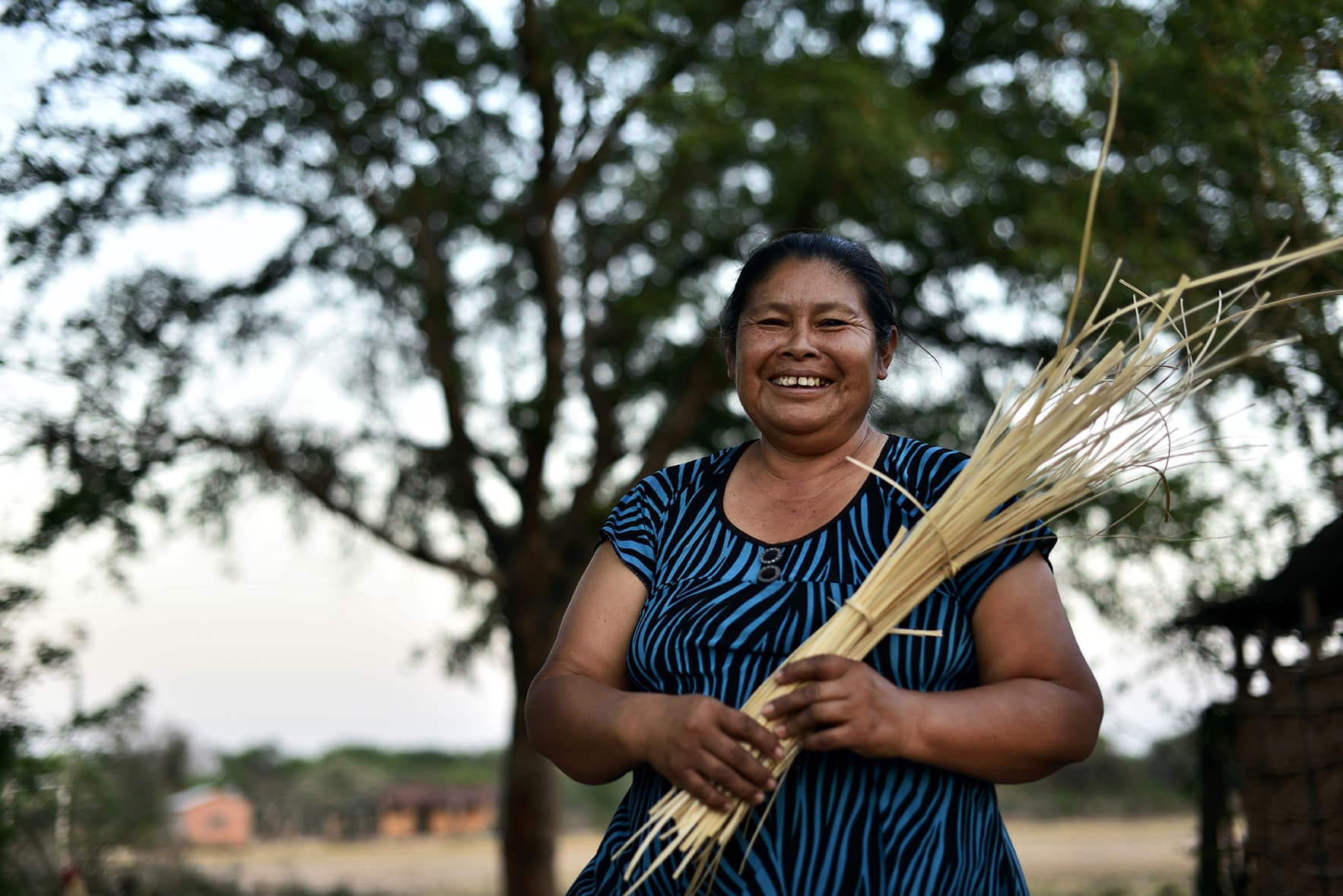Une femme avec un grand sourire tient dans ses mains des brins de blé, issus de l’agriculture familiale en Bolivie, avec le support du CIPCA, partenaire du CCFD-Terre Solidaire