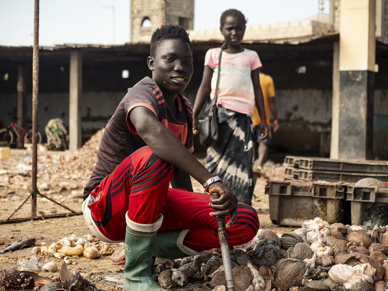 Un jeune homme travaille sur un port de pêcheur au Sénégal, en partenariat avec ADEPA.