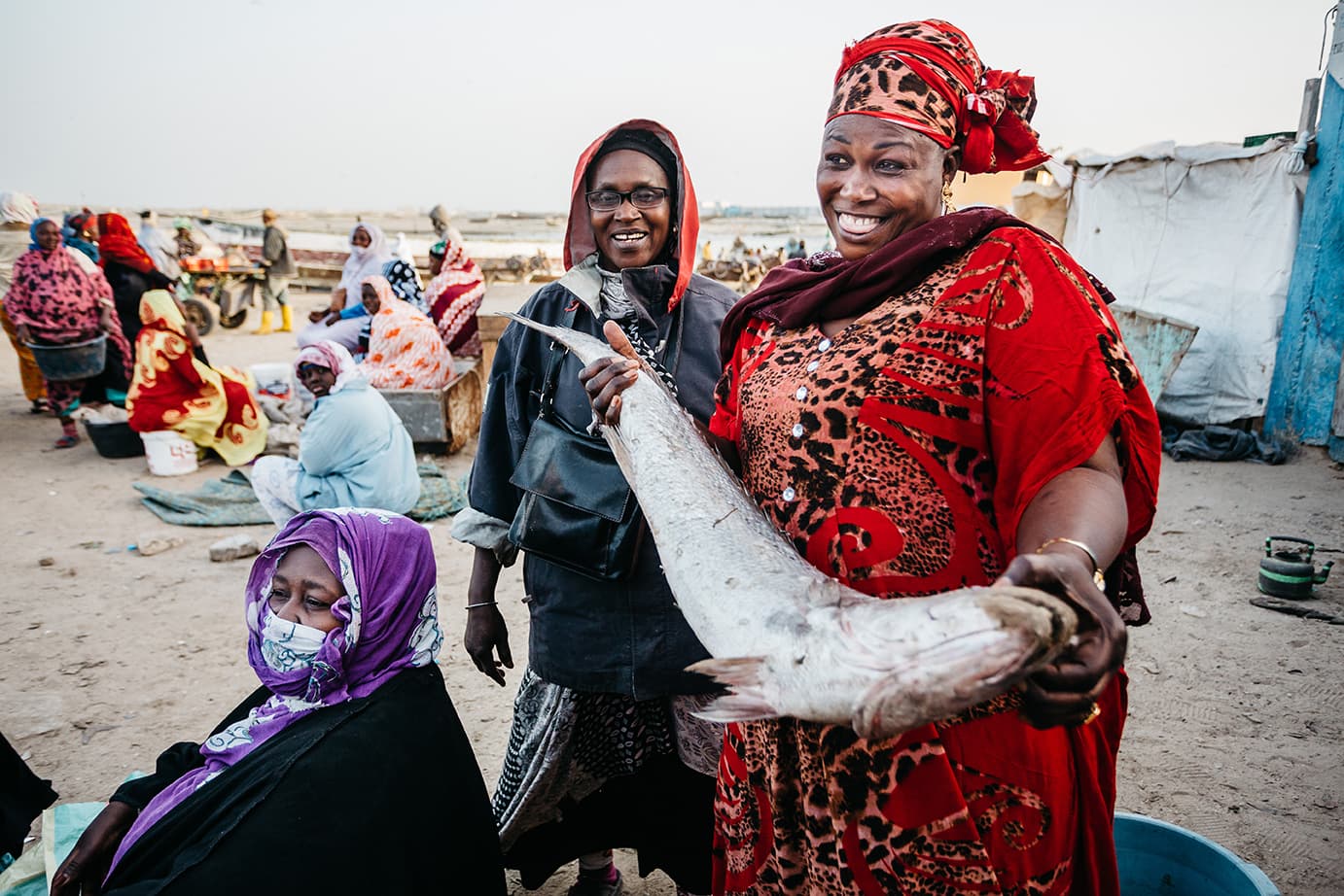 3 Femmes présentent avec le sourir un beau poisson frais issu de la pêche artisanale au Sénégal, en partenariat avec l’ADEPA